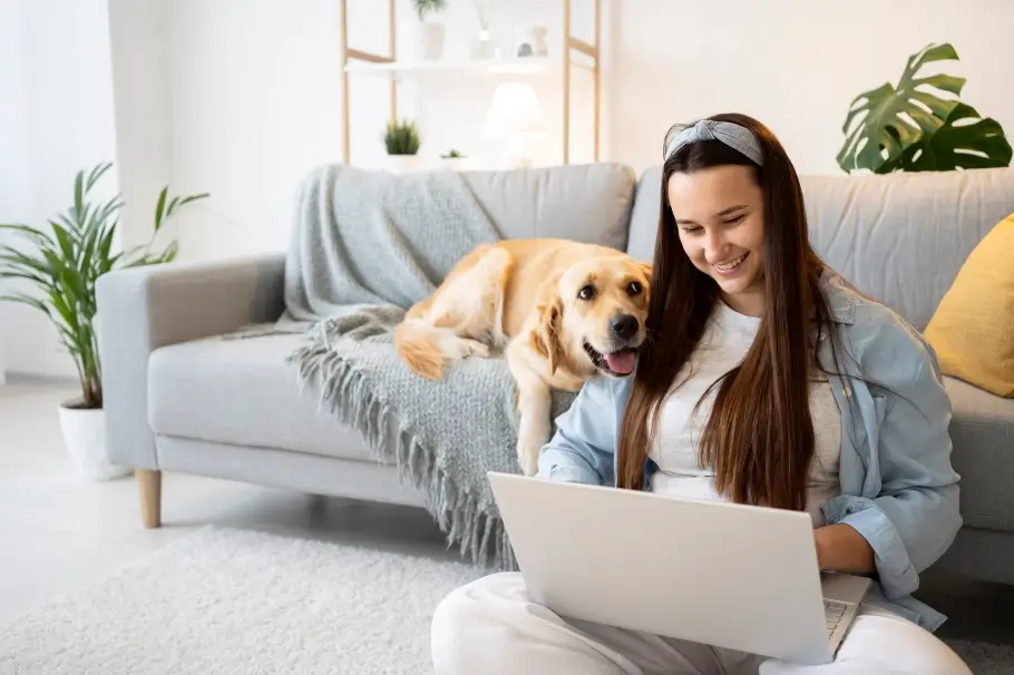 a student studying on her labtop with her dog laying next to her